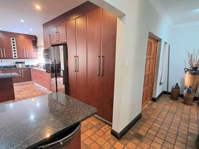 Spacious kitchen featuring dark wood cabinetry, granite countertops, built-in oven, gas hob, and tiled flooring, offering a functional layout with ample storage space.