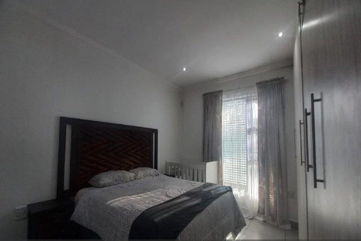 A bedroom featuring built-in cupboards, recessed ceiling lighting, and a window with curtain treatments.
