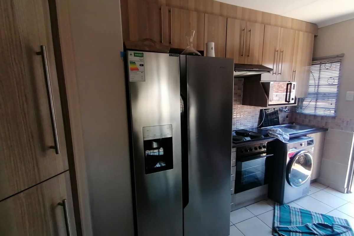 A functional kitchen featuring wood-look cabinetry, tiled splashbacks, a built-in oven with extractor fan, and integrated space for laundry appliances.