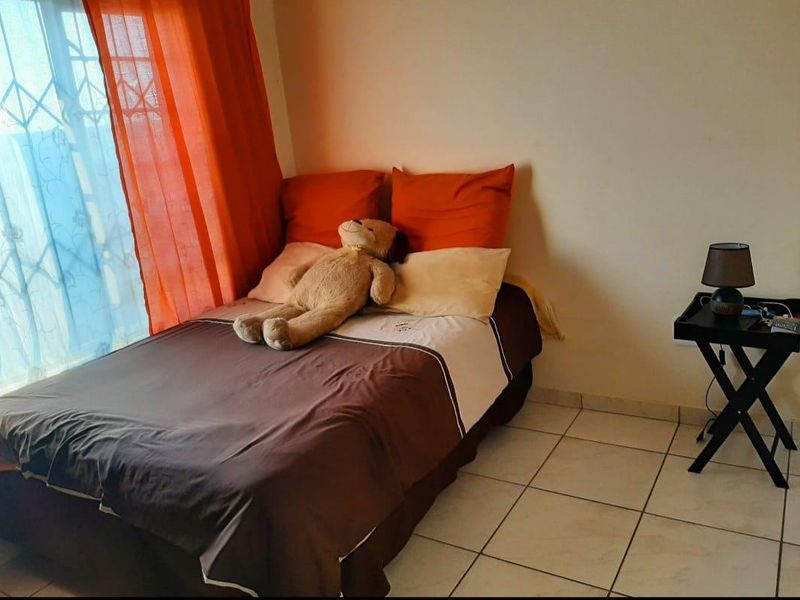 A functional bedroom featuring tiled flooring and a window fitted with a security gate.