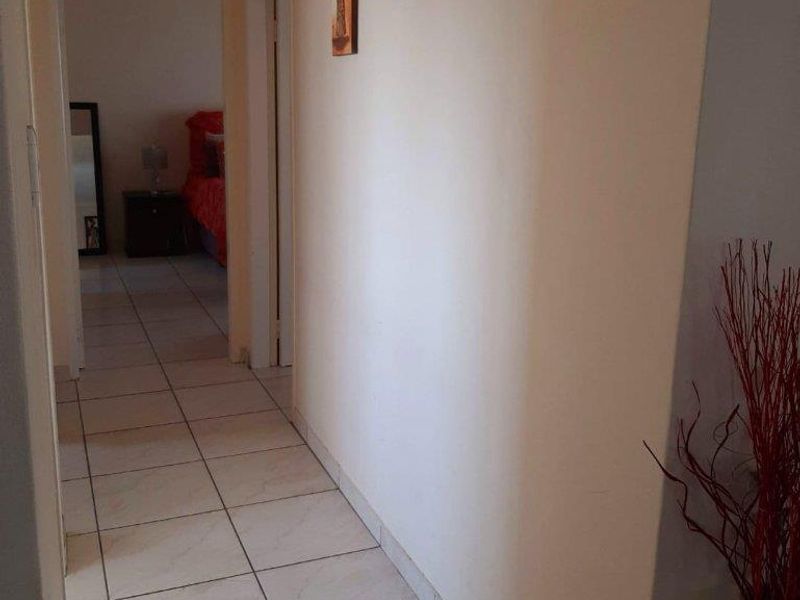 A functional hallway featuring neutral tiled flooring, providing access to adjacent rooms within the home.