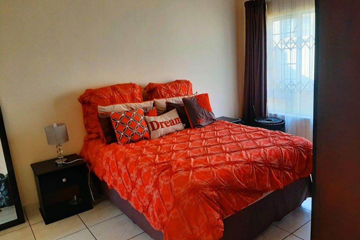 A bedroom featuring tiled flooring and a window fitted with a security gate and curtain rails.