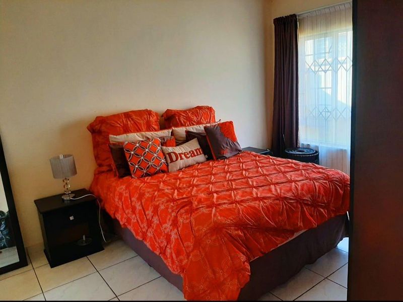 A bedroom featuring tiled flooring and a window fitted with a security gate and curtain rails.