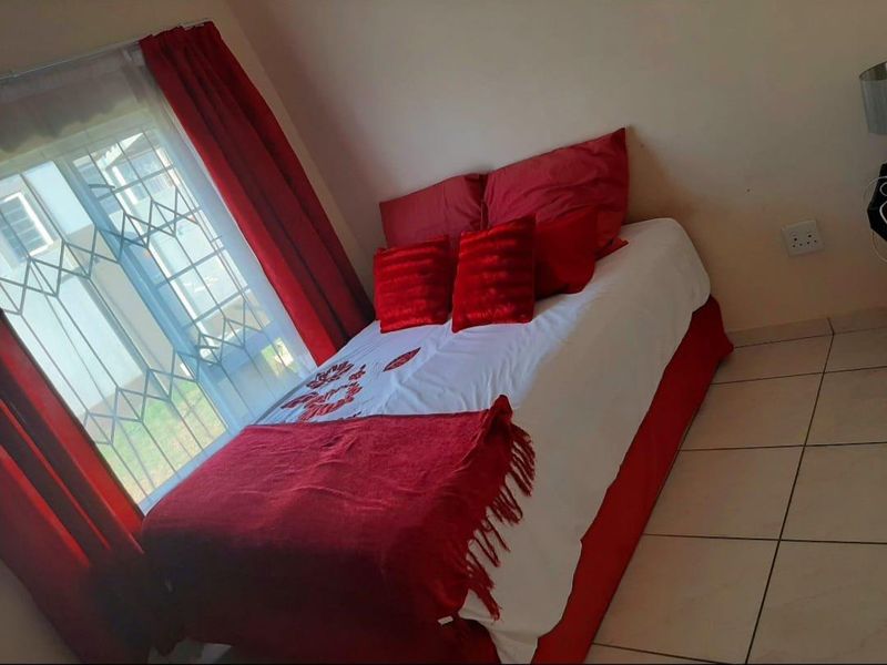 A bedroom featuring tiled flooring and a window fitted with a security gate, providing natural light.