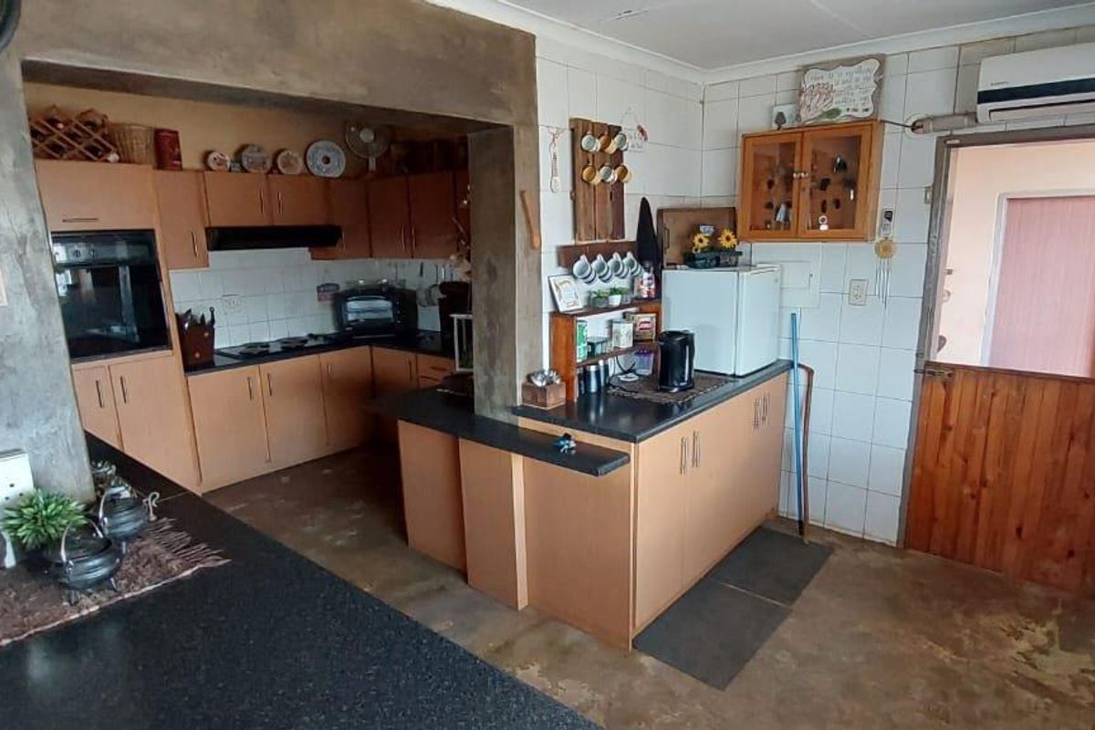 A functional kitchen featuring wooden cabinetry, built-in oven, hob, extractor fan, and a stable-style door leading to an adjacent area.