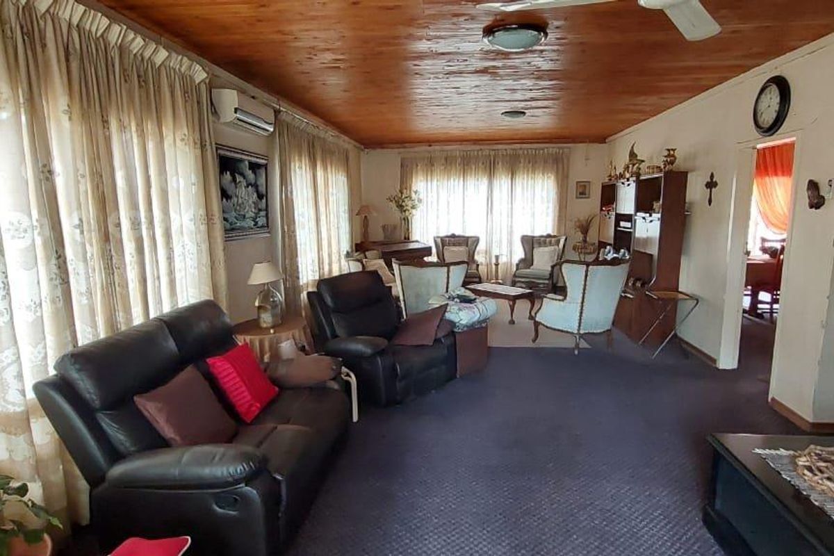 Spacious living room featuring a timber-paneled ceiling, wall-mounted air conditioning unit, and large windows with floor-to-ceiling curtains.