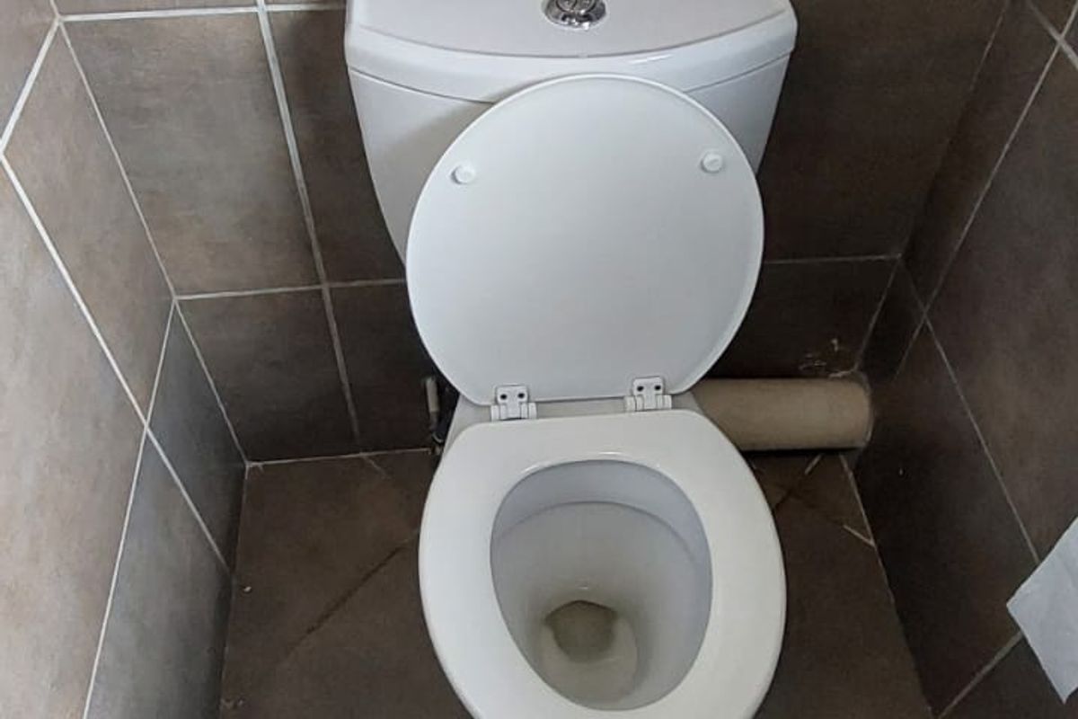 A compact bathroom featuring a standard white ceramic toilet with tiled walls and floor.