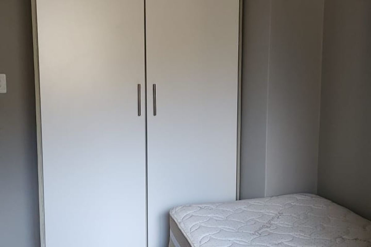 A bedroom featuring built-in white cabinetry and tiled flooring.