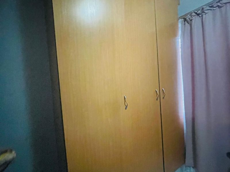 A bedroom featuring a large built-in wooden wardrobe with crown molding and tiled flooring.
