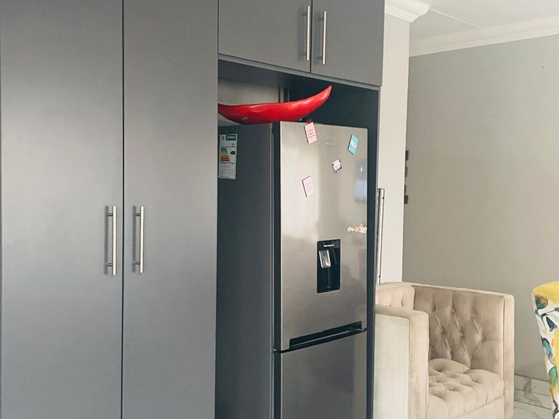 A modern kitchen area featuring sleek dark grey built-in cabinetry and polished marble-look floor tiles.