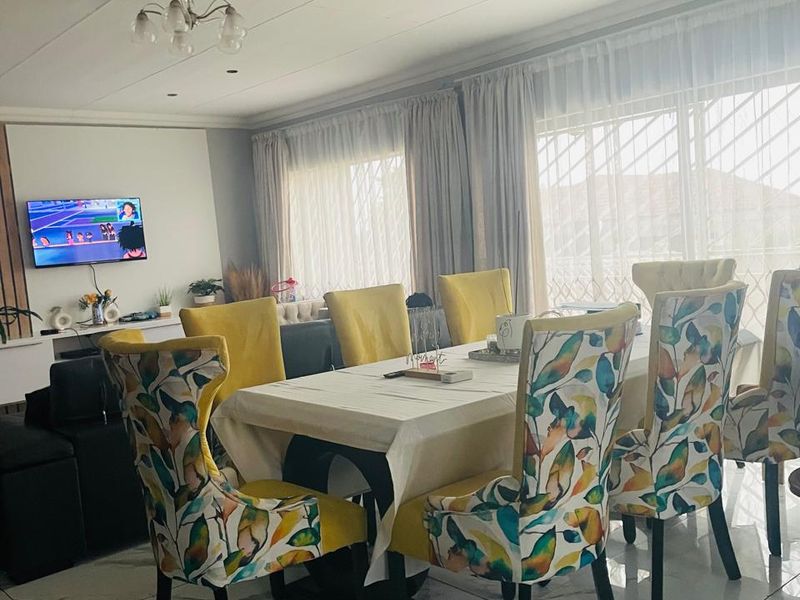 An open-plan living and dining area featuring polished marble-look floor tiles, recessed lighting, and large sliding glass doors with security gates.