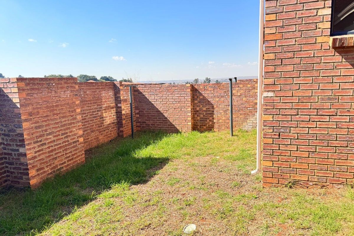 A private rear garden area featuring face-brick boundary walls and a small lawn, offering potential for landscaping or outdoor living development.