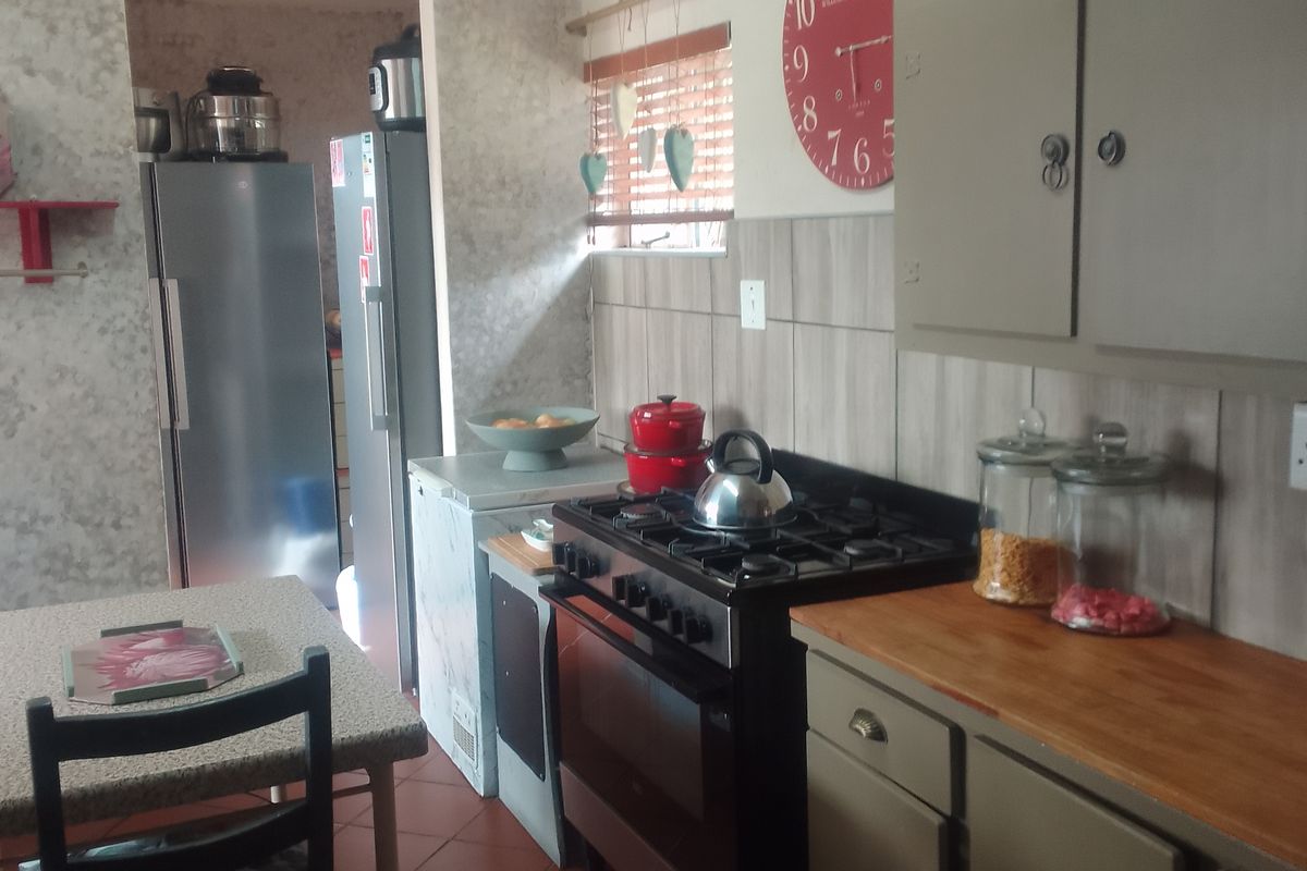 A functional kitchen featuring a gas stove, wooden countertops, tiled splashbacks, and built-in cabinetry with direct access to an adjacent utility area.