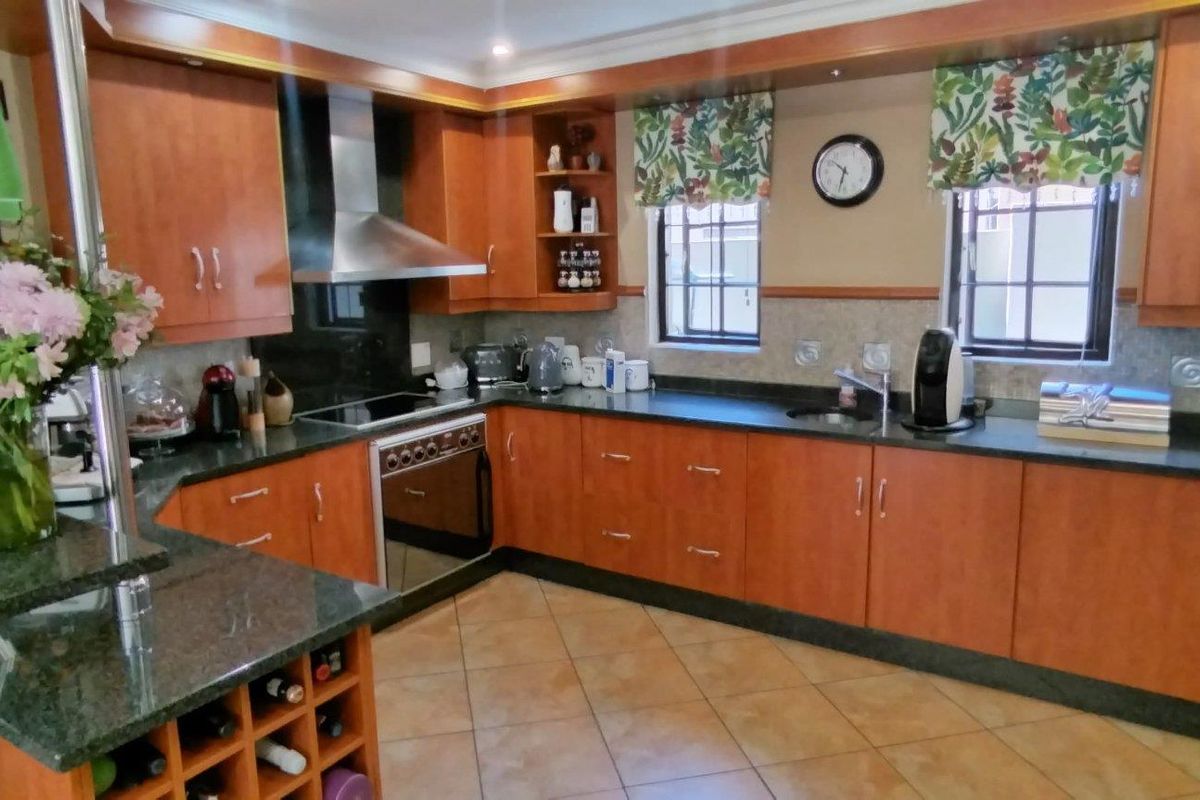 A functional U-shaped kitchen featuring wood-veneer cabinetry, dark granite countertops, a built-in oven, extractor fan, and tiled flooring.