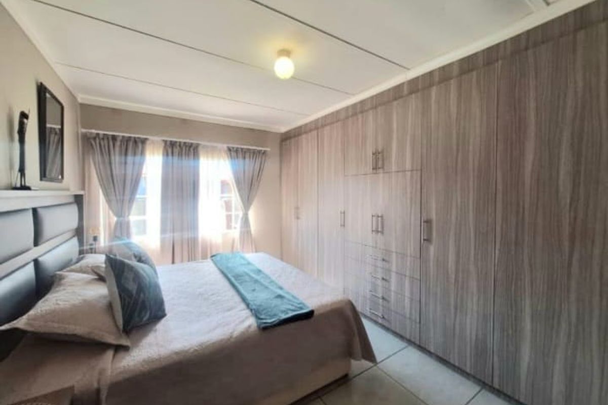 A well-maintained bedroom featuring extensive floor-to-ceiling built-in wooden cabinetry and tiled flooring.