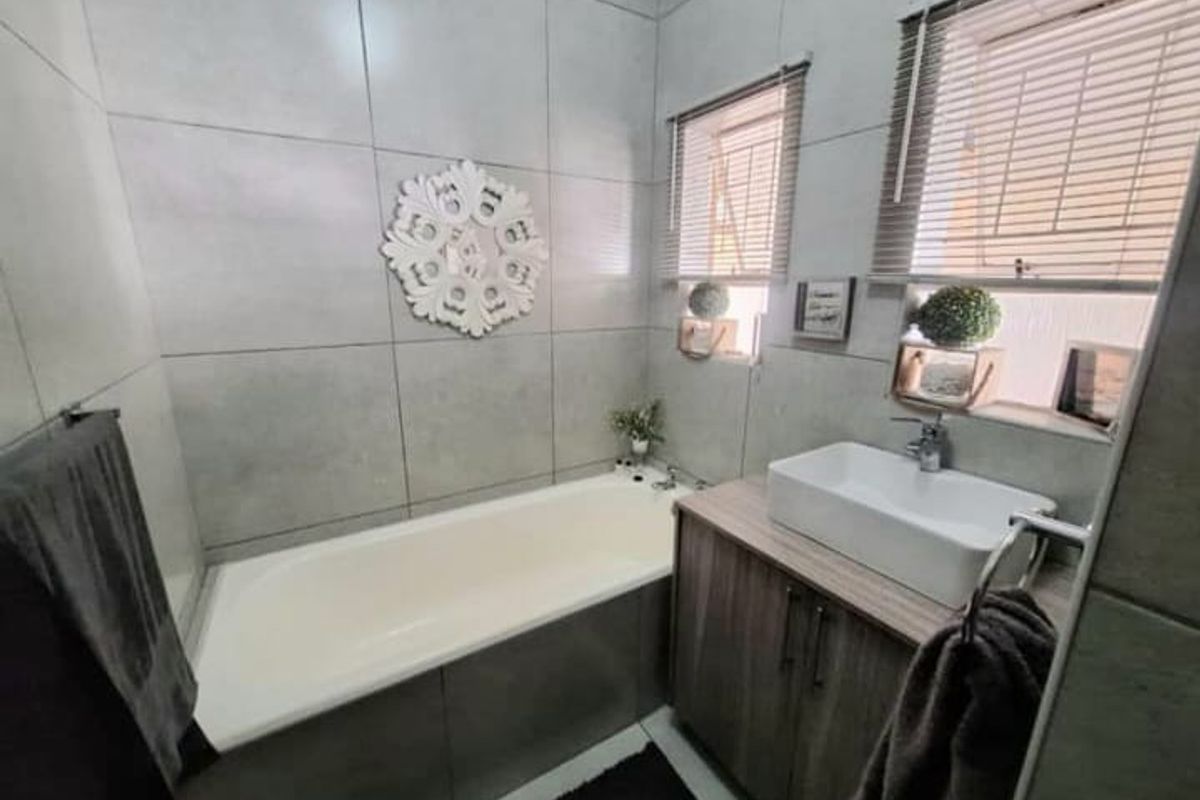 Modern bathroom featuring a built-in bathtub, a contemporary vessel sink vanity with storage, and large-format grey wall tiles.