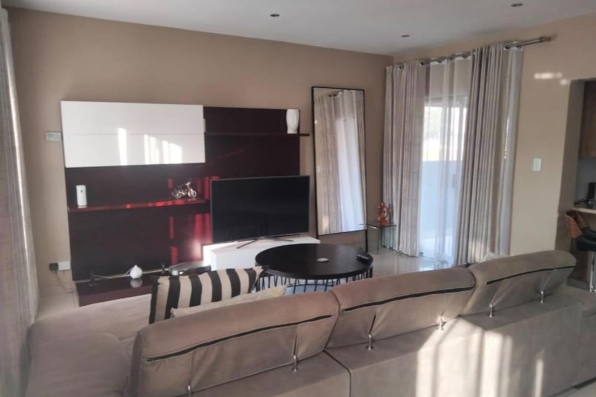 A well-maintained living room featuring neutral wall tones, recessed ceiling lighting, and large sliding glass doors providing access to the outdoor area.