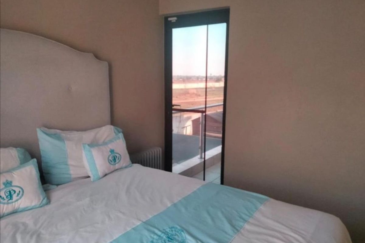 A well-maintained bedroom featuring a glass door that opens onto a private balcony, providing natural light and outdoor access.