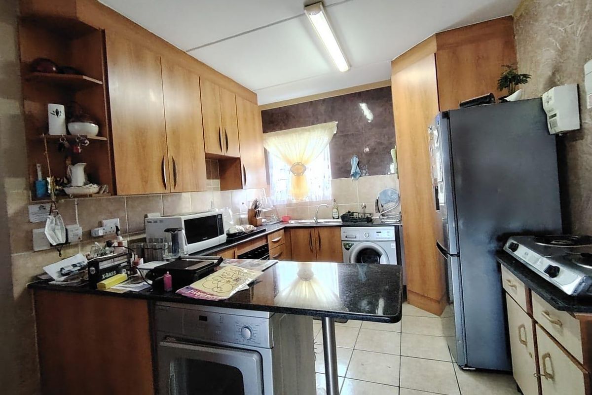 A functional kitchen featuring wooden cabinetry, granite countertops, a built-in oven, and integrated laundry plumbing, offering a practical layout for daily use.