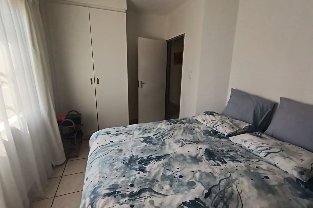 A functional bedroom featuring built-in cupboards and tiled flooring, offering a clean and simple living space.