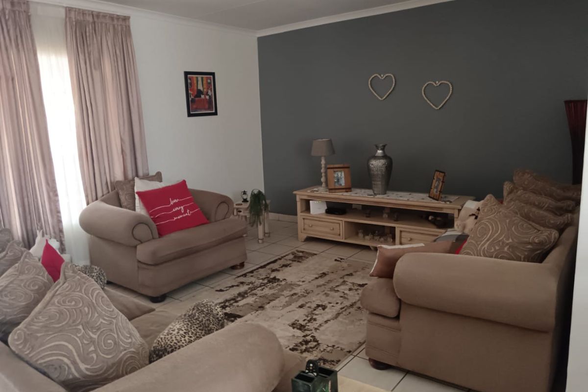 A comfortable living room featuring tiled flooring and a dark grey accent wall, providing a neutral base for interior design.