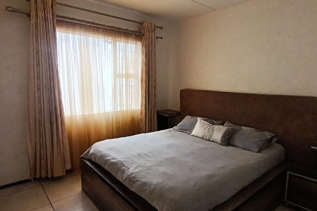 A bedroom featuring tiled flooring and a large window with curtain tracks, providing a functional and neutral living space.