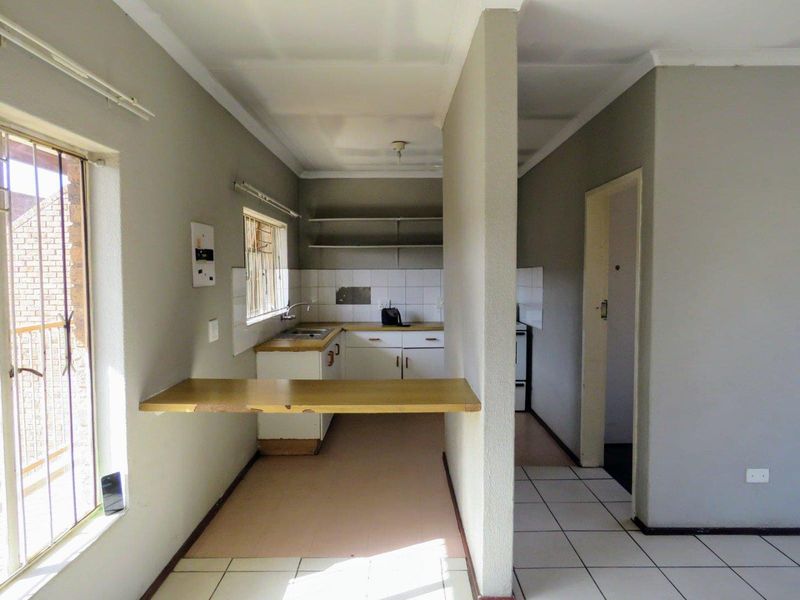 A functional, empty kitchen area featuring built-in cabinetry, a tiled splashback, and a breakfast bar, offering a blank canvas for renovation.