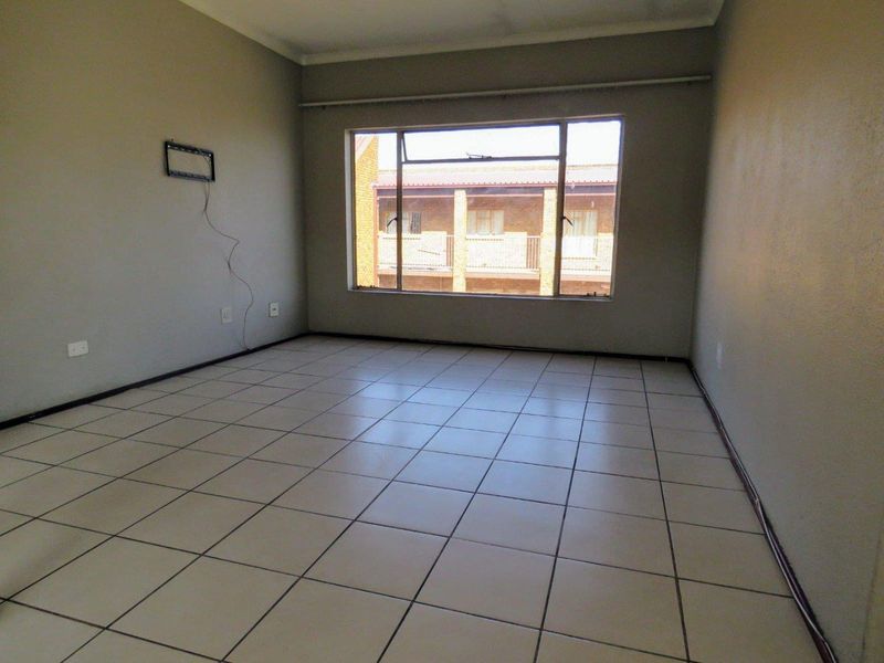 An empty living room featuring tiled flooring and a large window, providing a blank canvas for interior design and personalization.