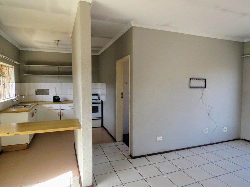 Open plan living and kitchen area featuring tiled flooring, built-in cabinetry, and a breakfast counter, presenting a blank canvas for renovation.