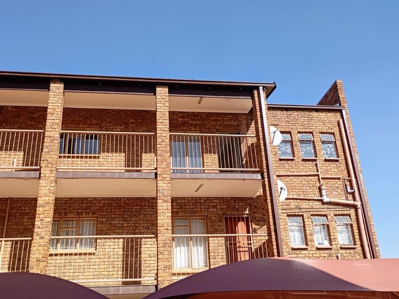 Exterior view of a multi-story apartment building featuring face brick construction, metal balcony railings, and multiple window units.