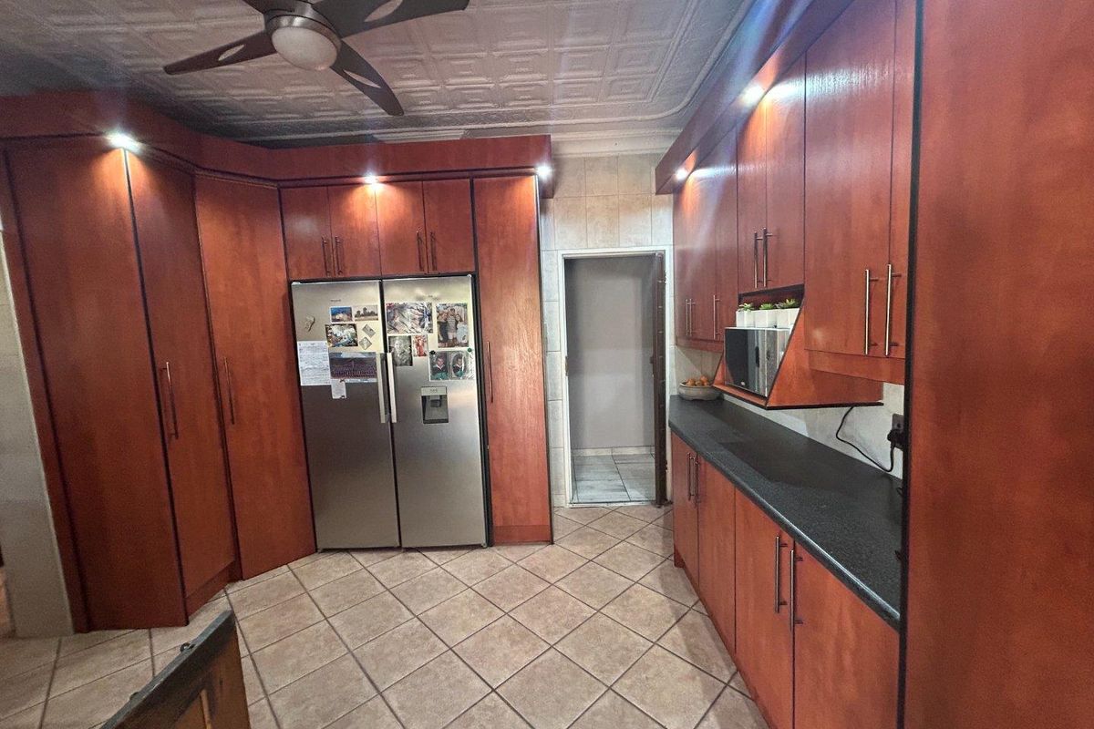 A functional kitchen featuring dark wood cabinetry, stone-look countertops, integrated lighting, and a tiled floor with a decorative ceiling finish.
