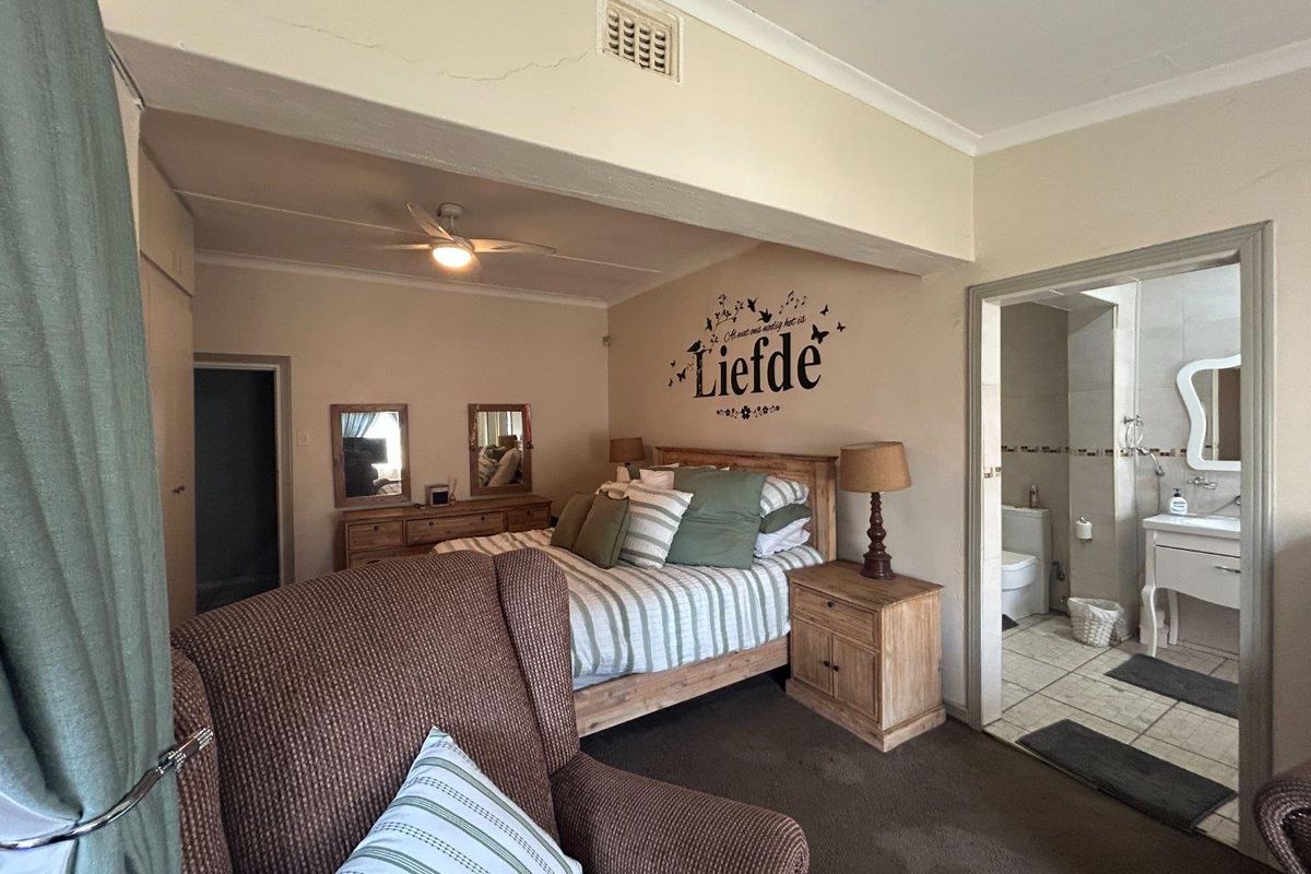 A bedroom featuring a ceiling fan, built-in cupboards, and an en-suite bathroom with tiled flooring.