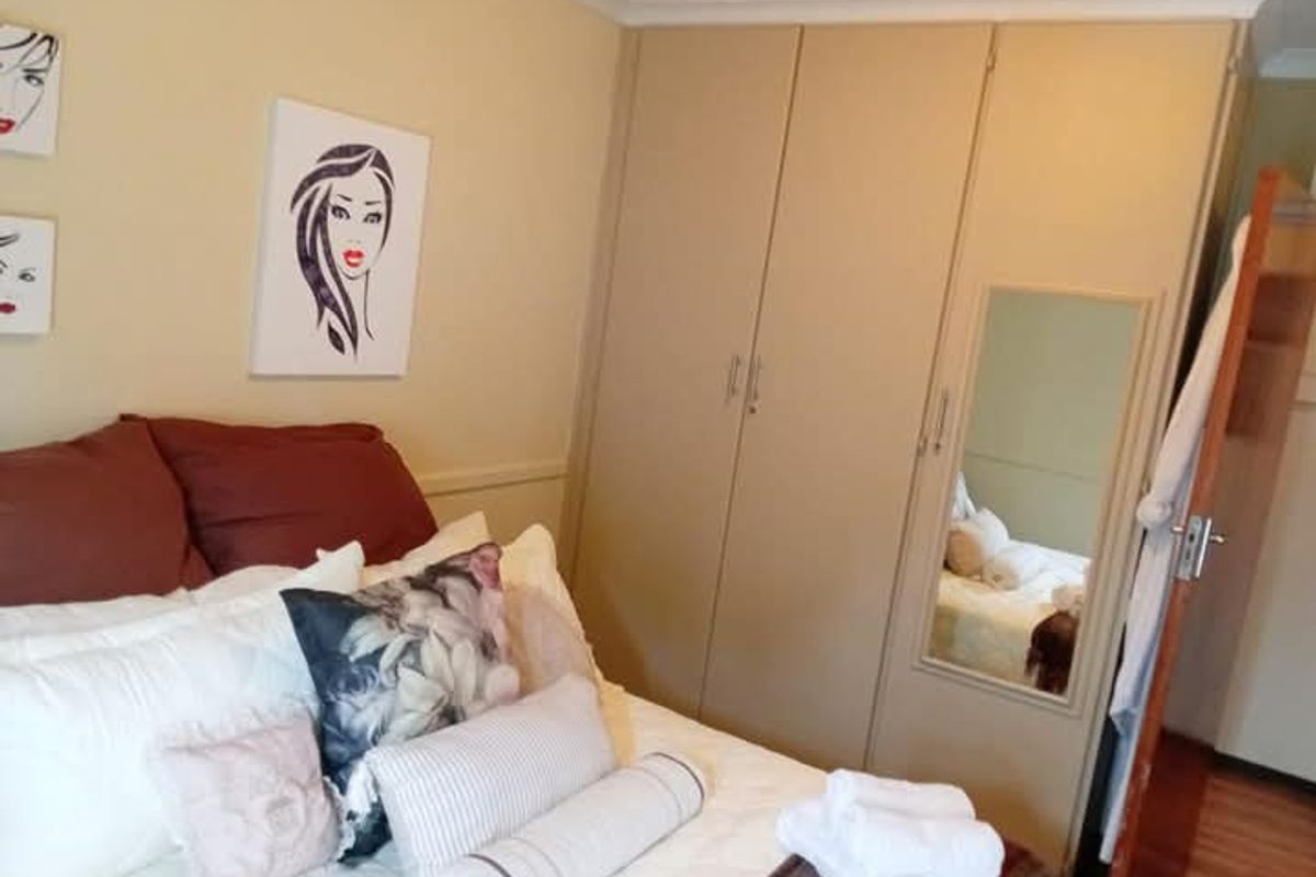 A bedroom featuring built-in cupboards with a mirrored panel and decorative coving.