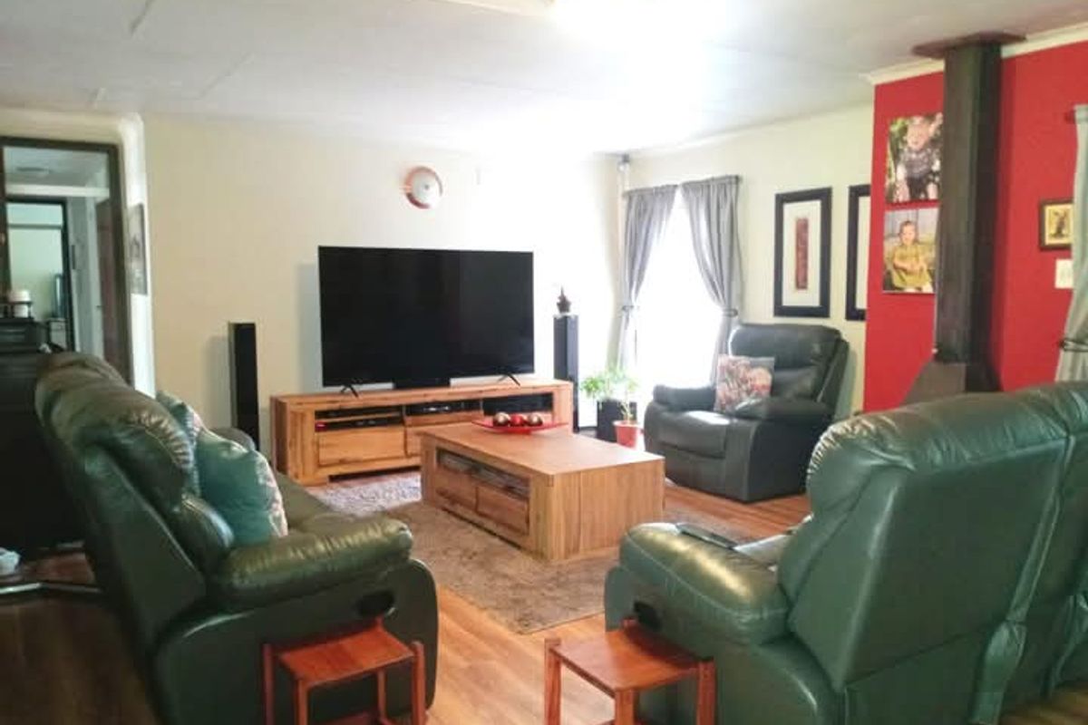 Spacious living room featuring laminate flooring and a prominent wood-burning fireplace with a red accent wall.