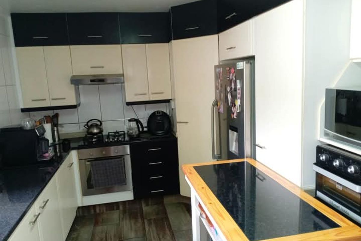 A functional kitchen featuring two-tone cabinetry, granite countertops, a gas hob, and an integrated oven with tiled flooring.