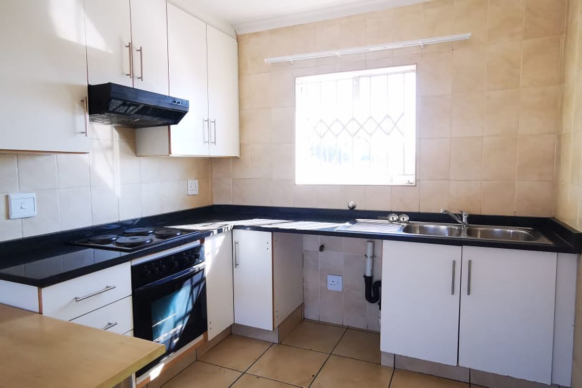A functional kitchen featuring white cabinetry, black countertops, a built-in oven and hob, and tiled walls and flooring.