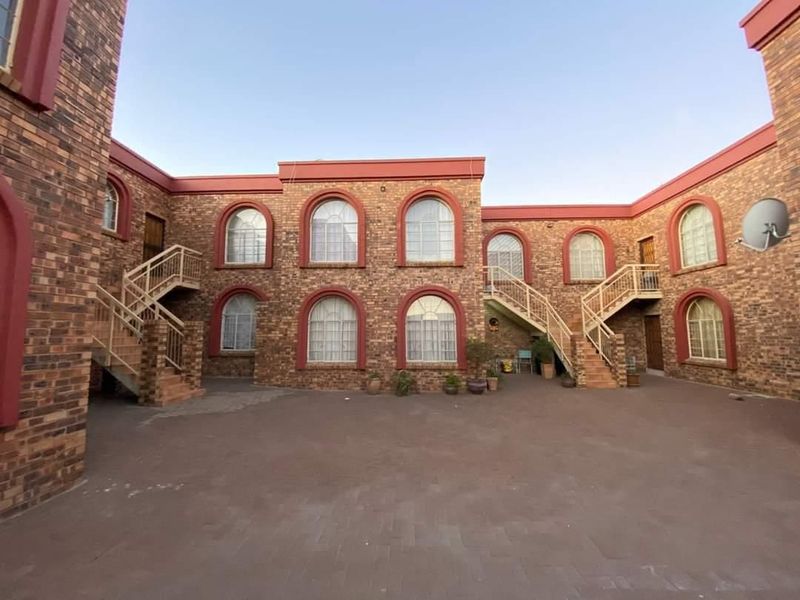 A view of the apartment complex courtyard featuring face brick exterior walls, arched windows, and external metal staircases providing access to upper levels.