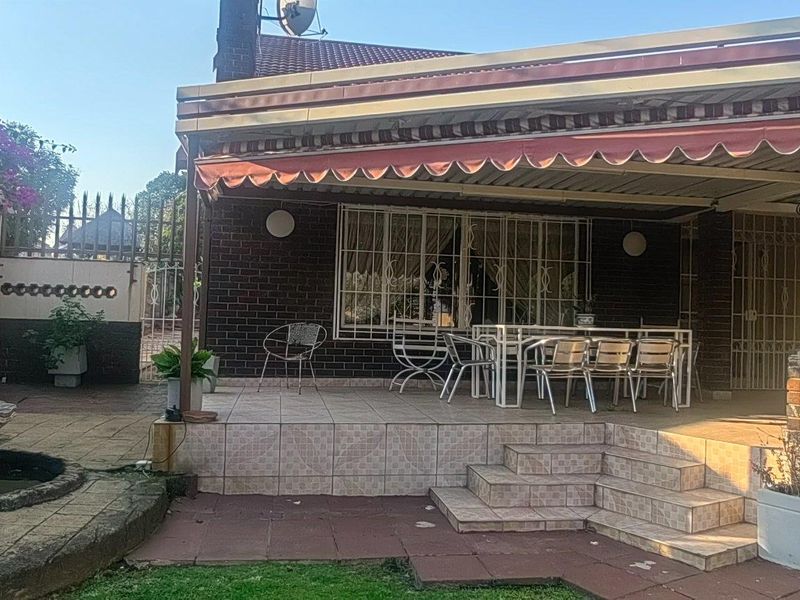 Covered outdoor patio area featuring tiled flooring, a retractable awning, and an adjacent garden fountain, providing a functional space for outdoor entertaining.
