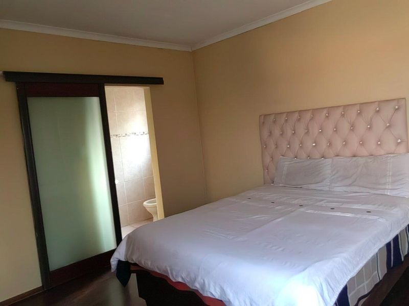 A bedroom featuring laminate flooring and a sliding door leading to an en-suite bathroom.