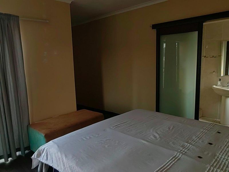 Bedroom featuring a sliding glass door to a balcony and an en-suite bathroom with a pedestal sink and frosted glass door.
