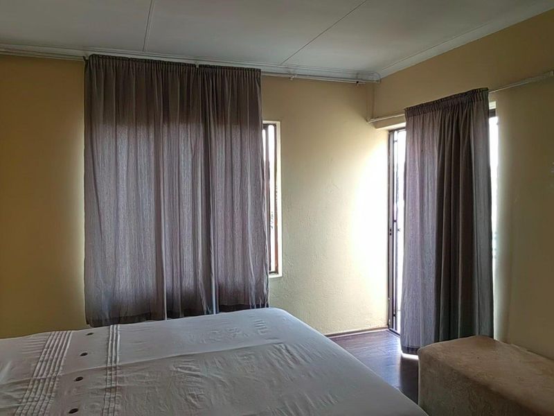 A bedroom featuring laminate flooring, neutral wall tones, and direct access to an outdoor area via a sliding door.