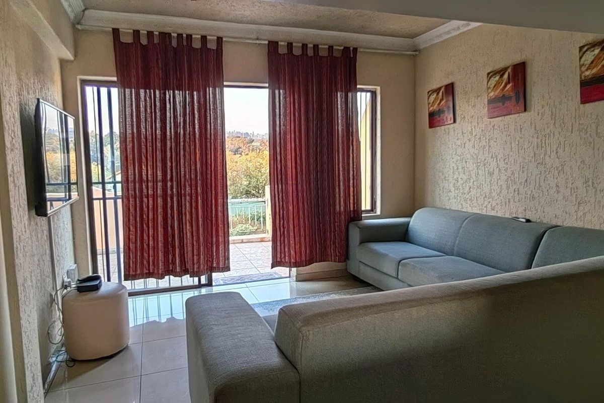 A living room featuring tiled floors, textured walls, and a sliding glass door providing access to an outdoor balcony area.