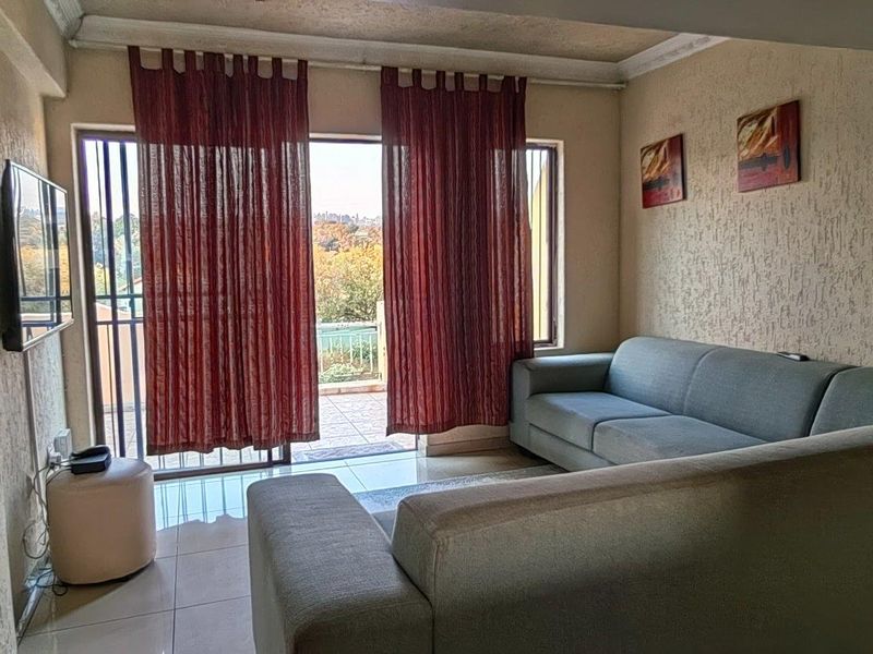 A living room featuring tiled floors, textured walls, and a sliding glass door providing access to an outdoor balcony area.
