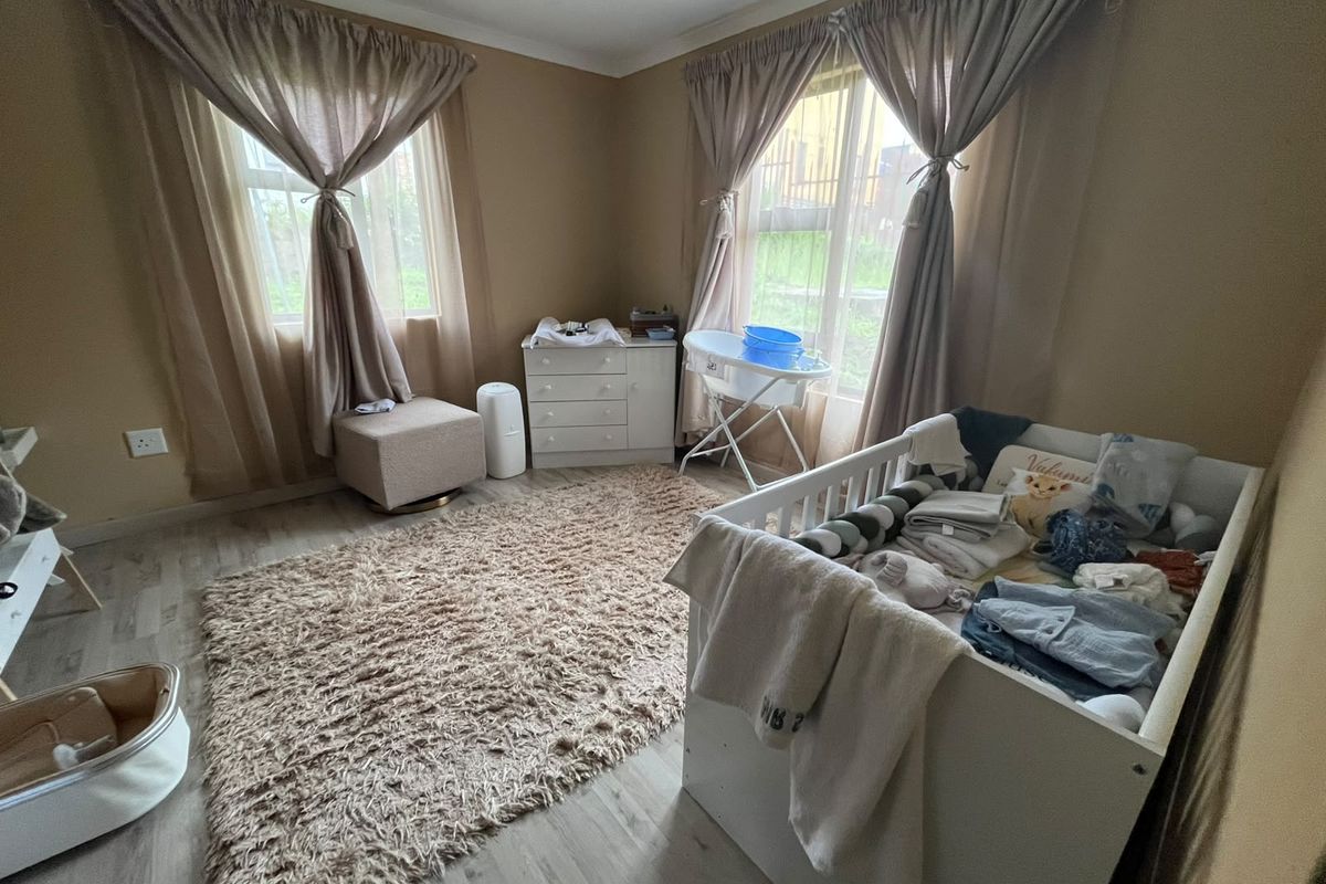 A bedroom featuring laminate flooring and dual windows with curtain rails, providing natural light and a neutral color palette.