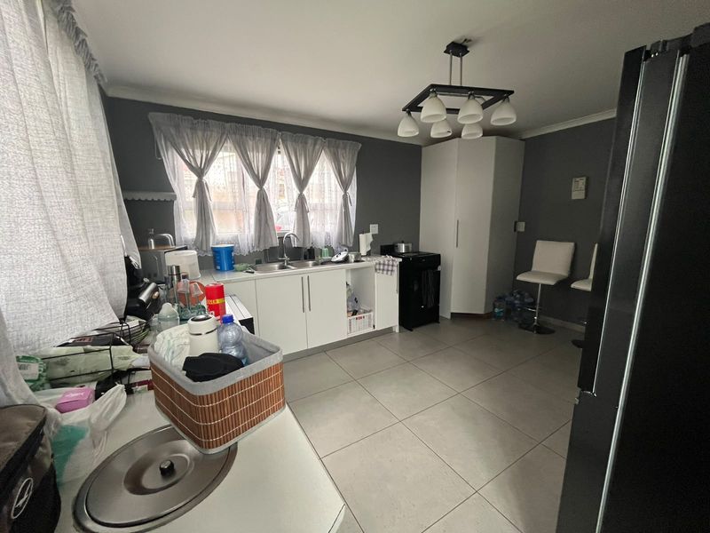 A functional kitchen featuring white cabinetry, tiled flooring, and a central pendant light fixture, providing a practical workspace with ample room for updates.