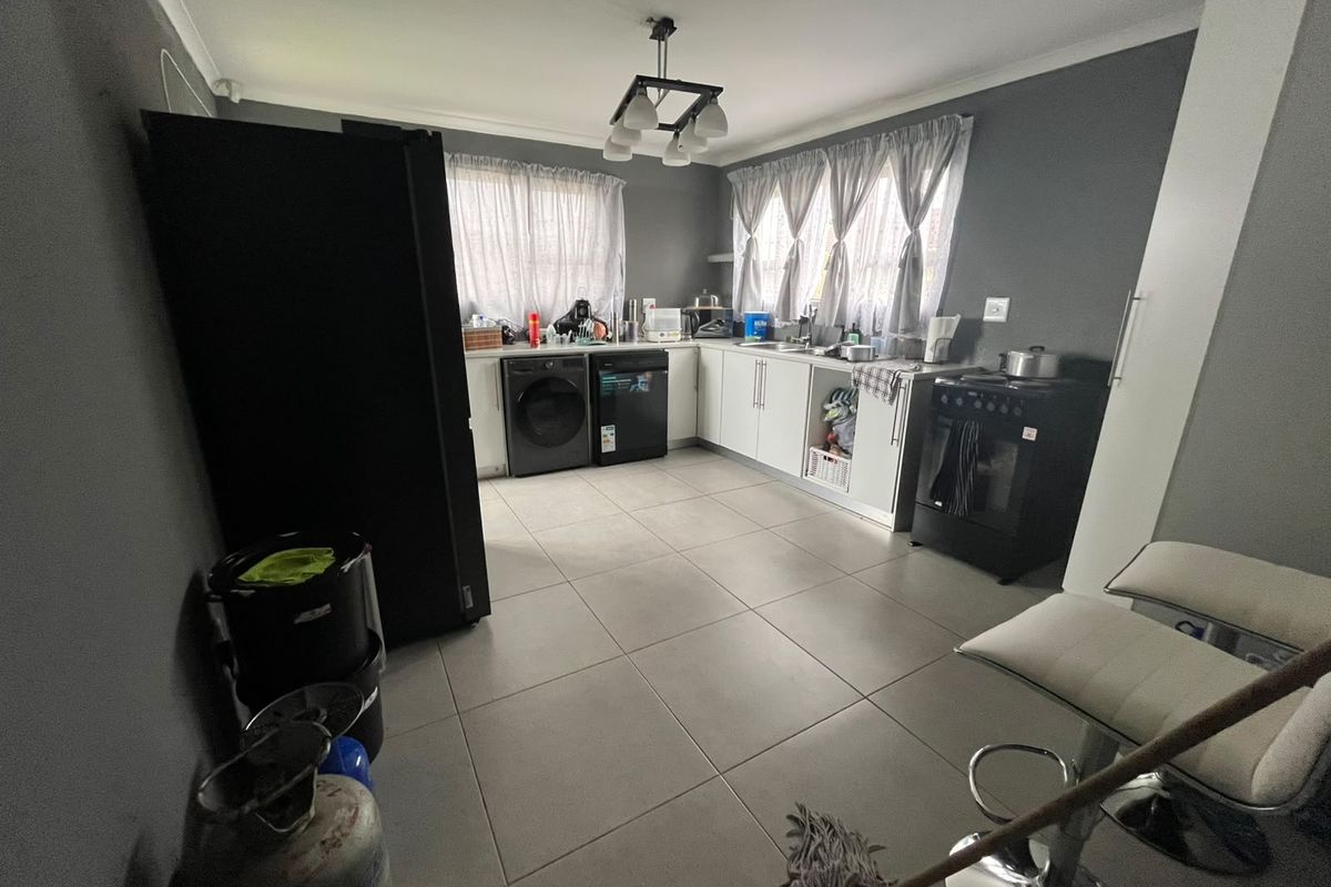 Functional kitchen featuring tiled flooring, built-in cabinetry, and space for laundry appliances, offering a practical layout for daily use.