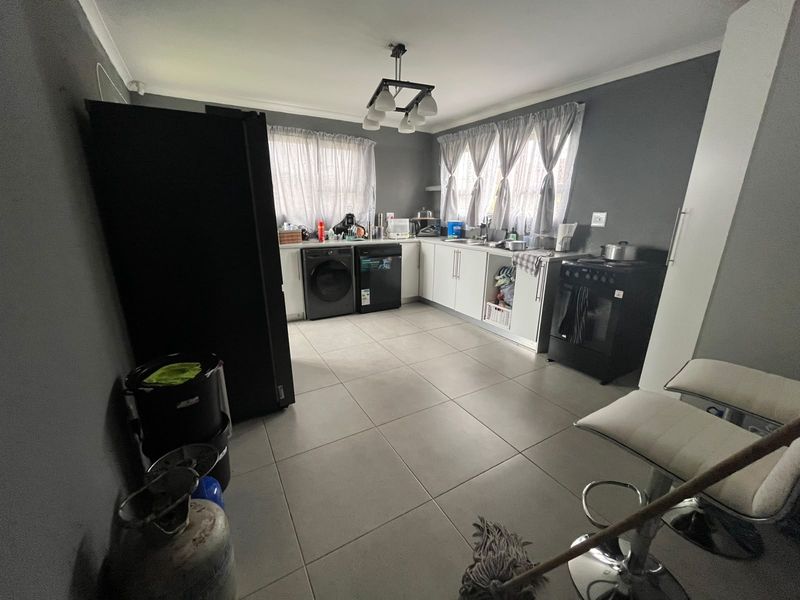 Functional kitchen featuring tiled flooring, built-in cabinetry, and space for laundry appliances, offering a practical layout for daily use.