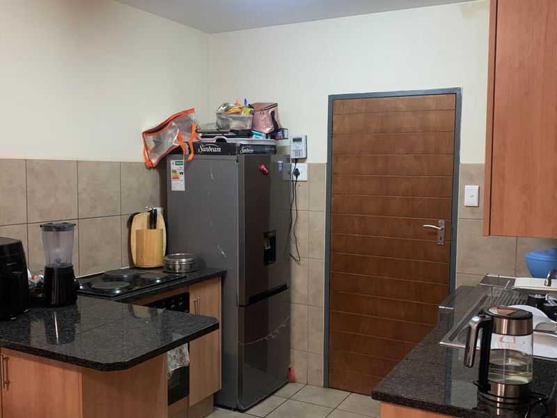 A functional kitchen featuring granite countertops, built-in cabinetry, an electric hob, and a tiled backsplash, providing a practical workspace for daily cooking.