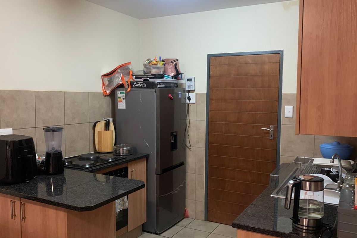 A functional kitchen featuring granite countertops, built-in cabinetry, an electric hob, and a tiled backsplash, providing a practical workspace for daily cooking.