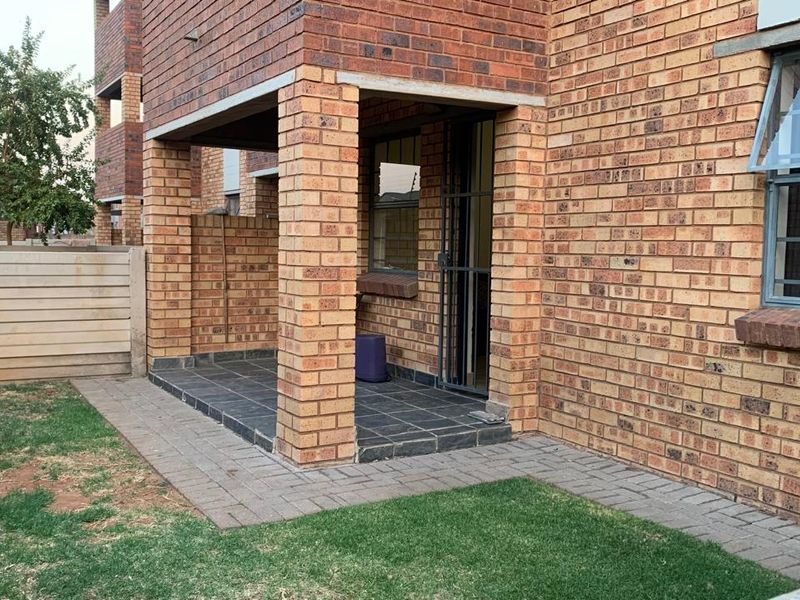 A ground-floor patio area featuring brick construction, tiled flooring, and a security gate, providing direct access to the garden space.